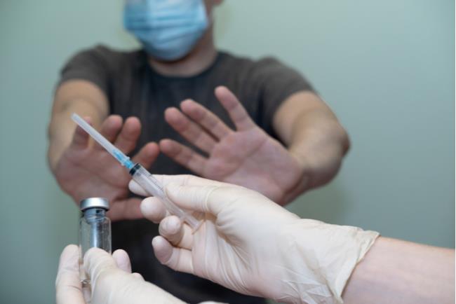 גבר מסמן לרוקח לעצור עם ידיו לפני קבלת חיסון נגד קורונה 